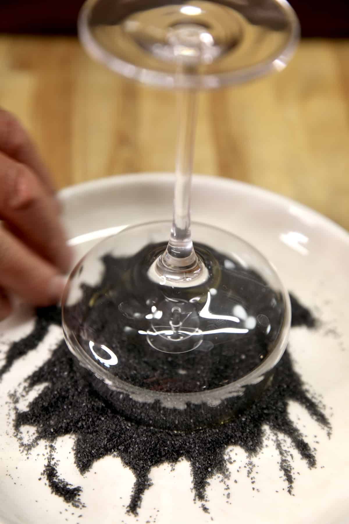 Garnishing cocktail glass rim with black lava salt.
