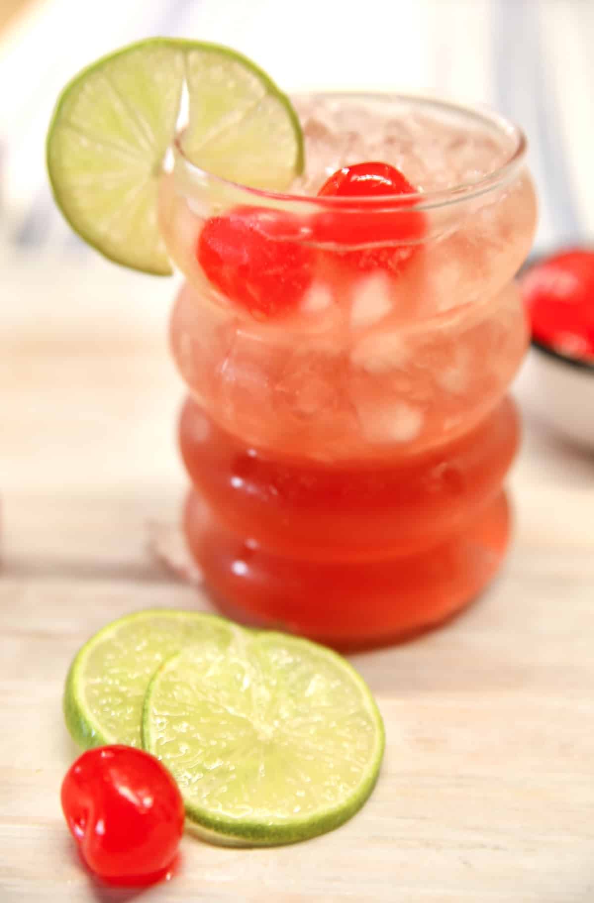 Glass with cherry limeade wine punch. Cherry and lime garnishes.