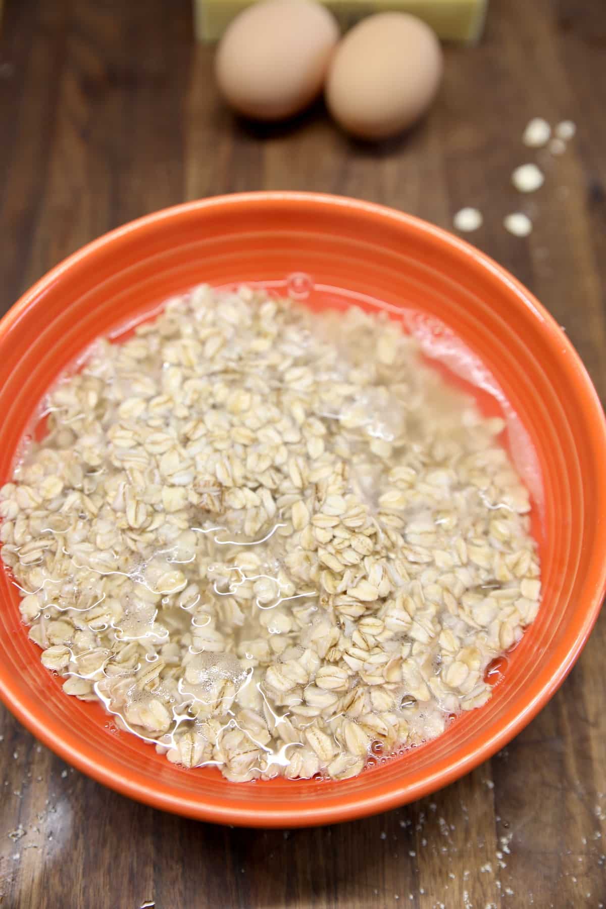 Oats and boiling water in an orange bowl.