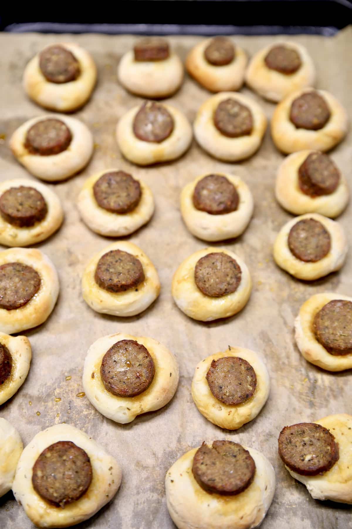 Pizza dough and smoked sausage bites on a baking sheet.