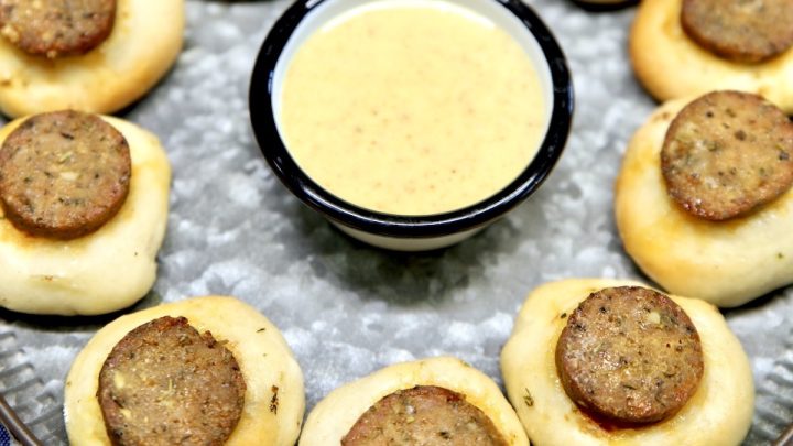 Smoked sausage bites with pizza dough and mustard sauce on a platter.