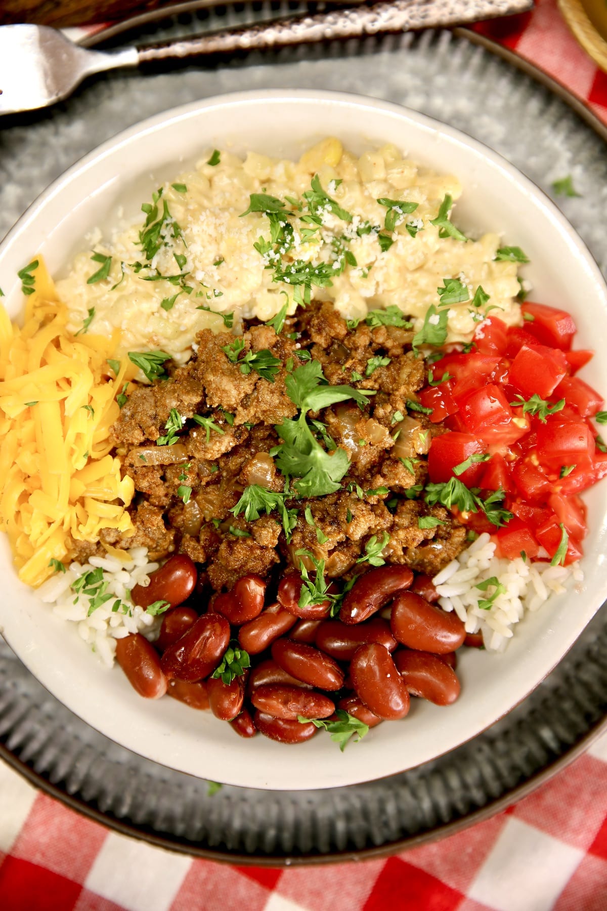 Closeup of burrito bowl with ground beef, tomatoes, rice, corn and beans.
