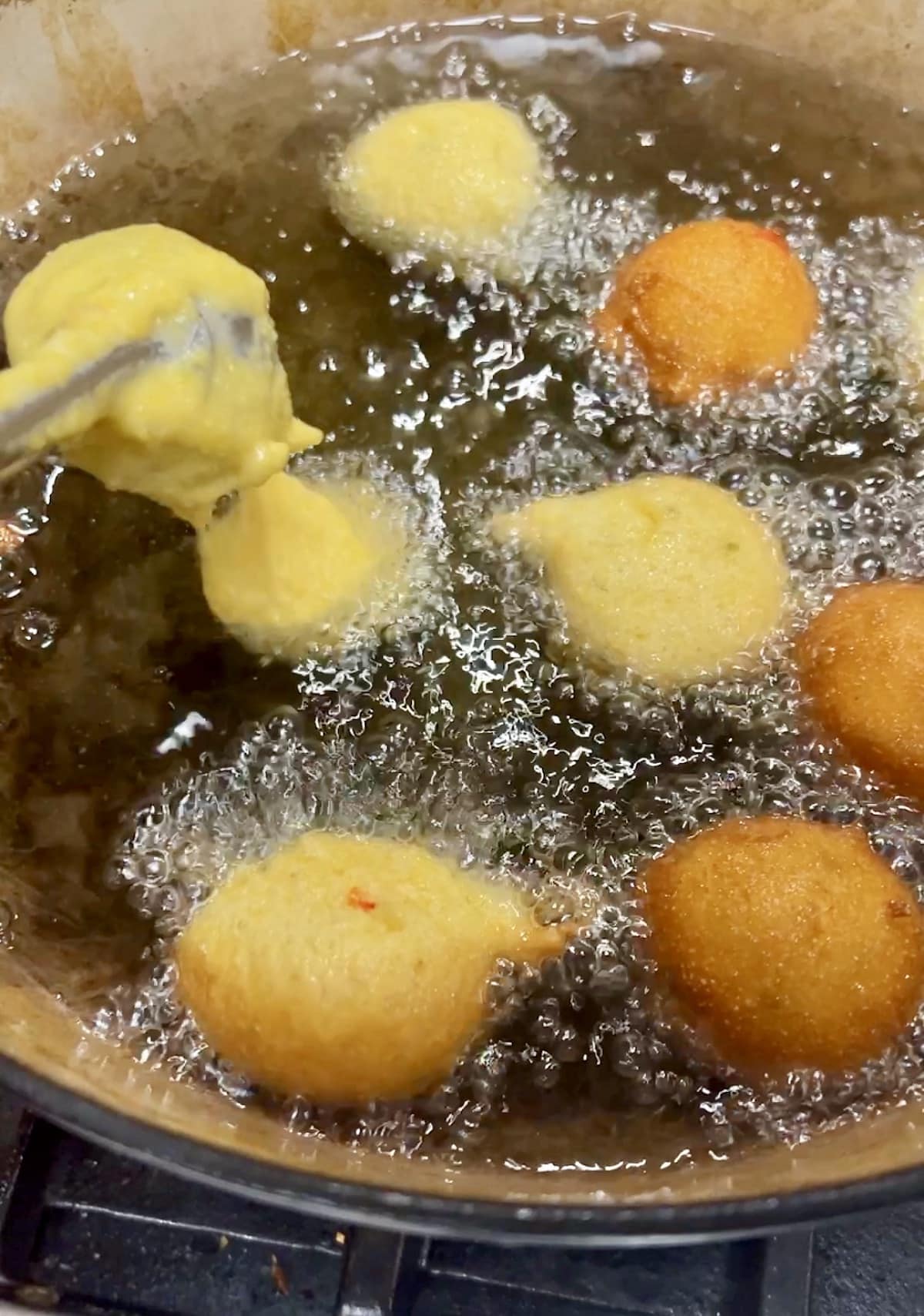 Dropping hush puppy batter into hot oil using a cookie scoop.