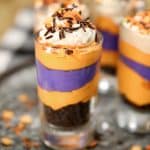 Layered Halloween no bake cheesecake with Oreo crumbs in a dessert glass.