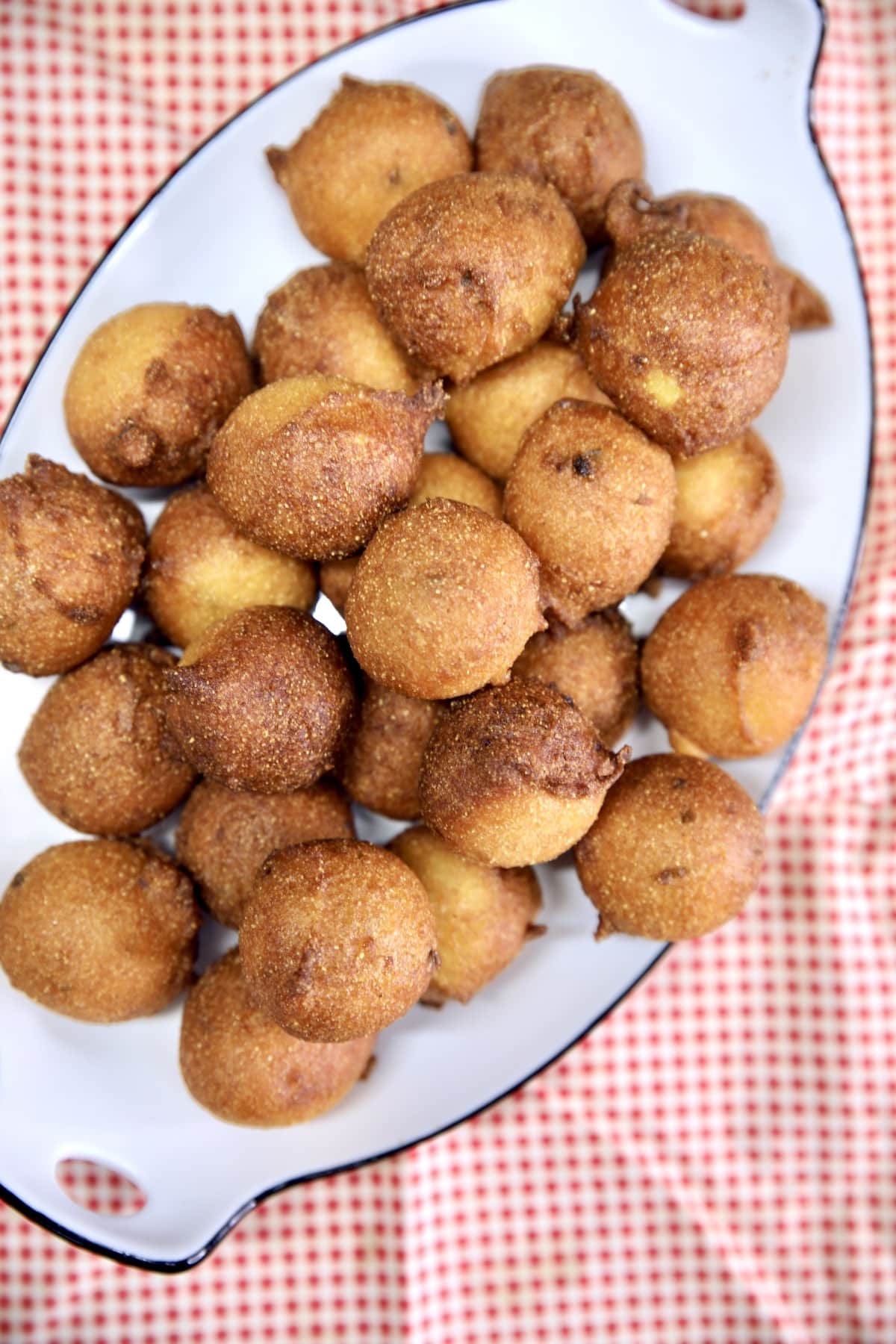 Platter of hush puppies on a red gingham cloth.