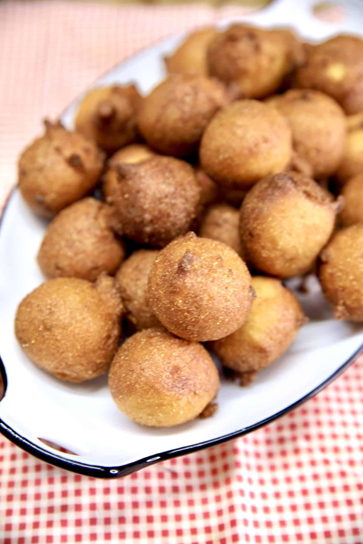 Platter of hush puppies on a red check cloth.