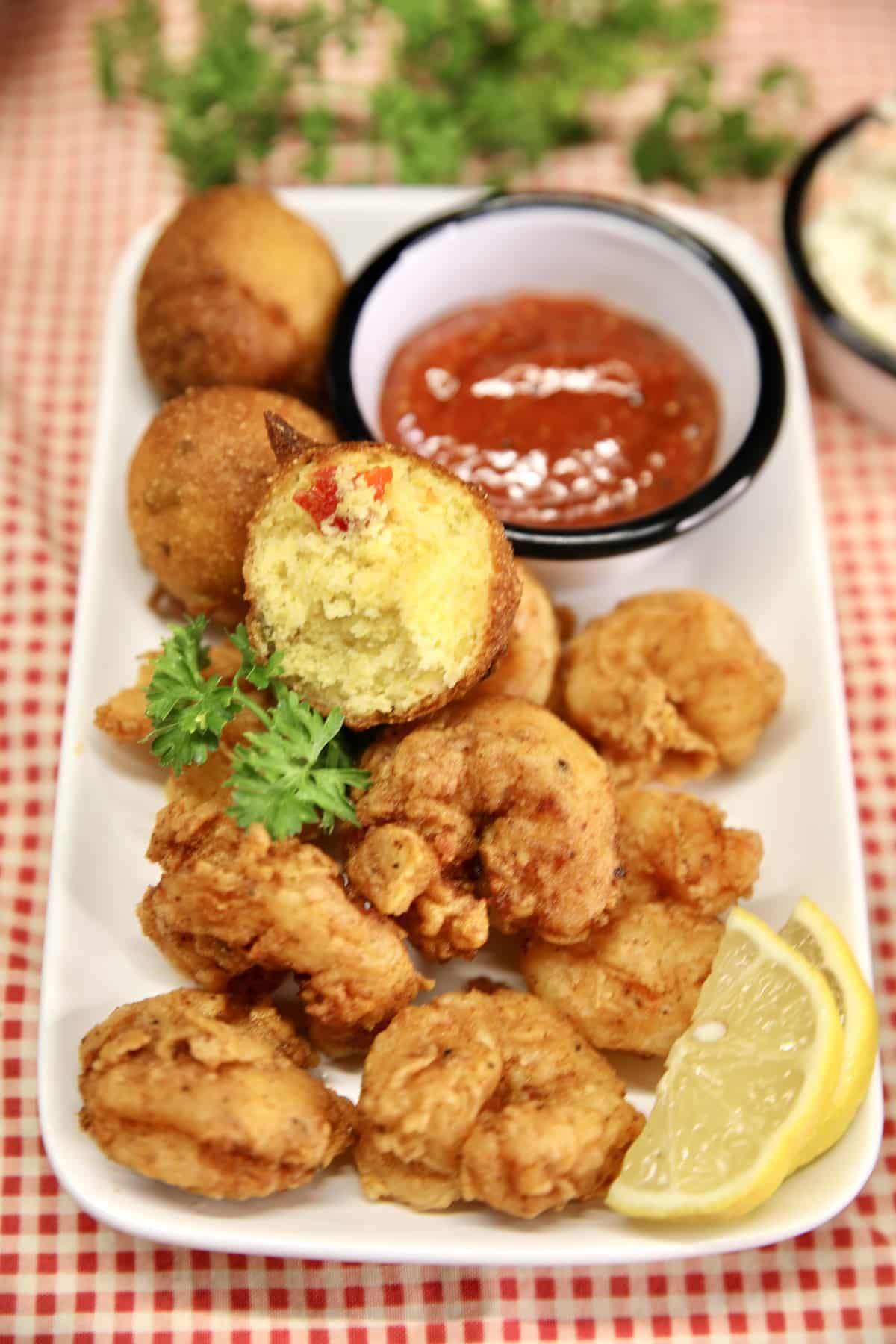 Platter of shrimp and hush puppies with cocktail sauce.