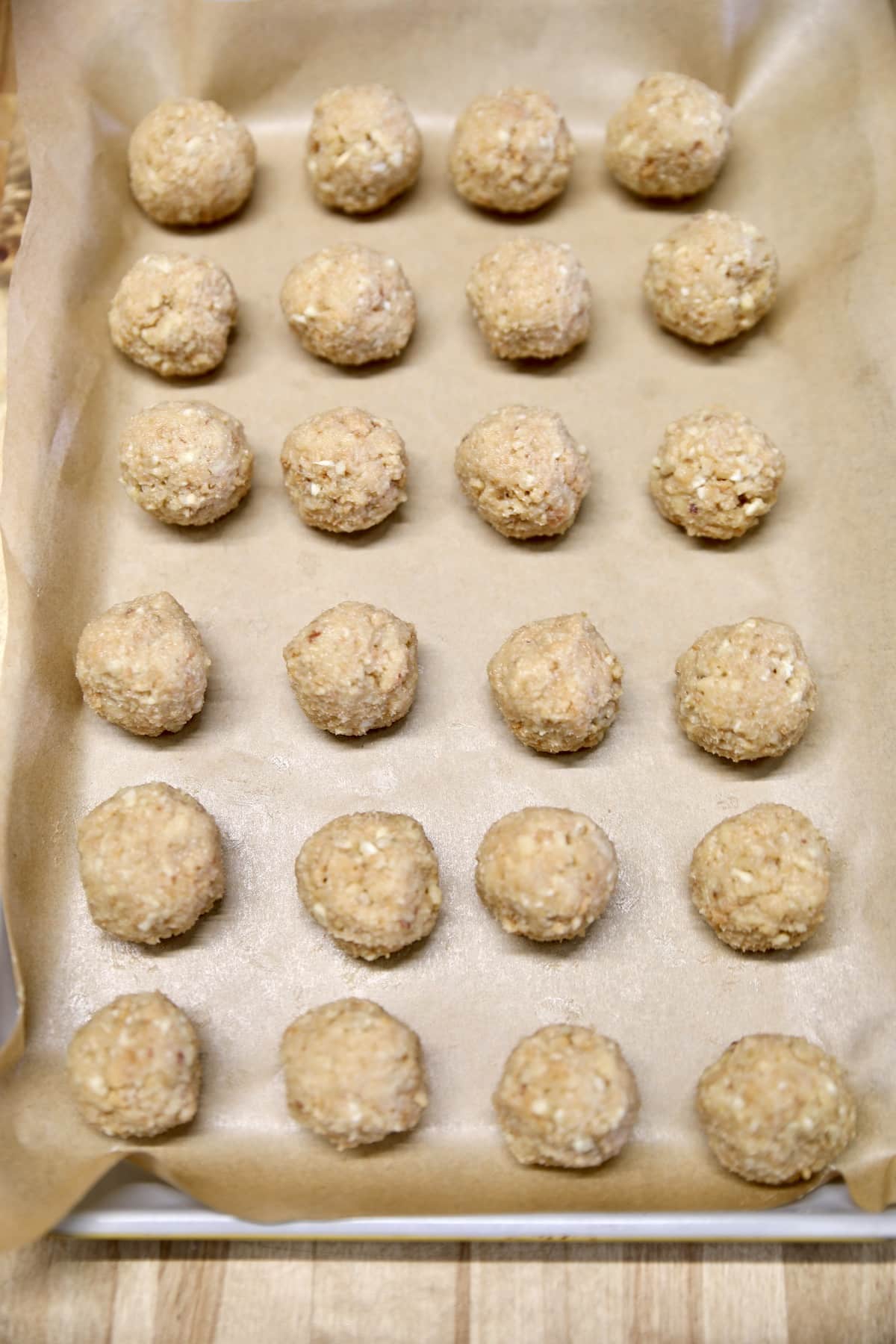 Sheet pan lined with parchment with pecan bourbon balls.