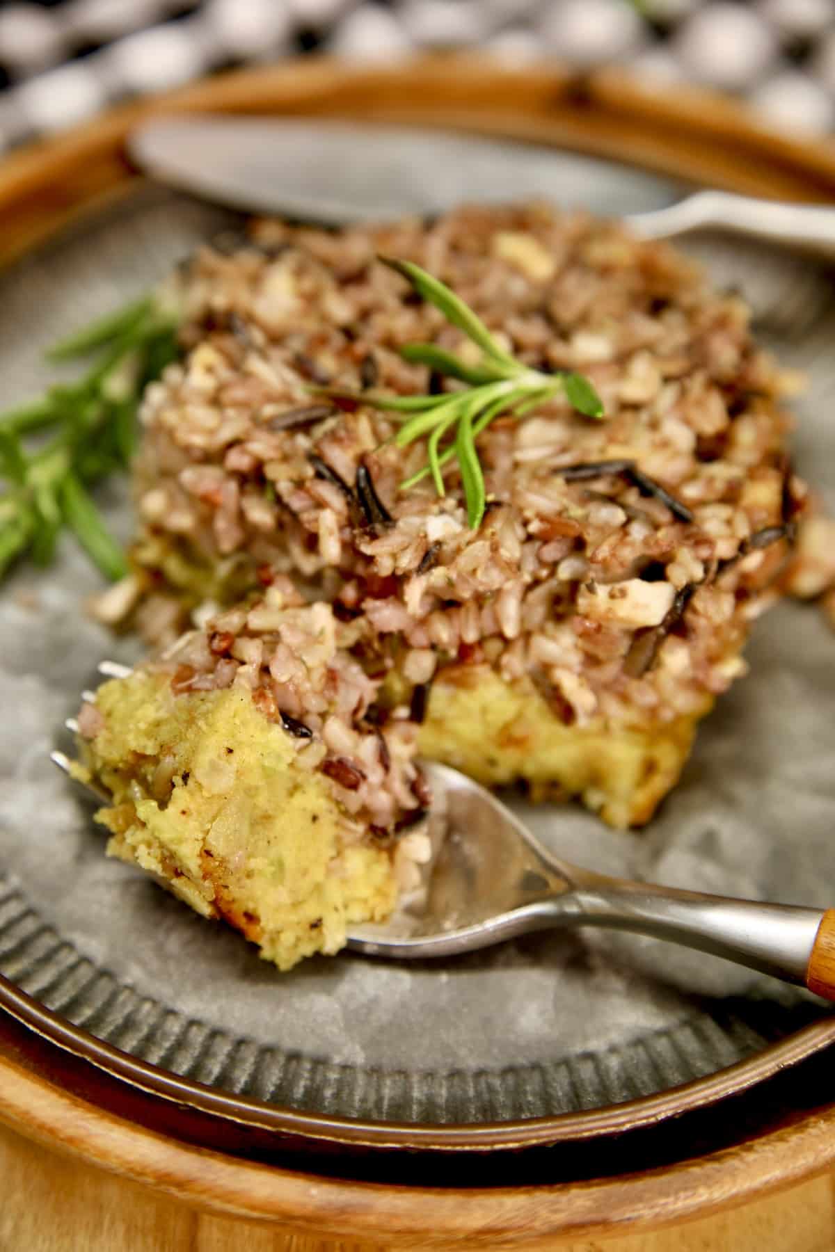 Cornbread wild rice dressing on a plate with bite on a fork.