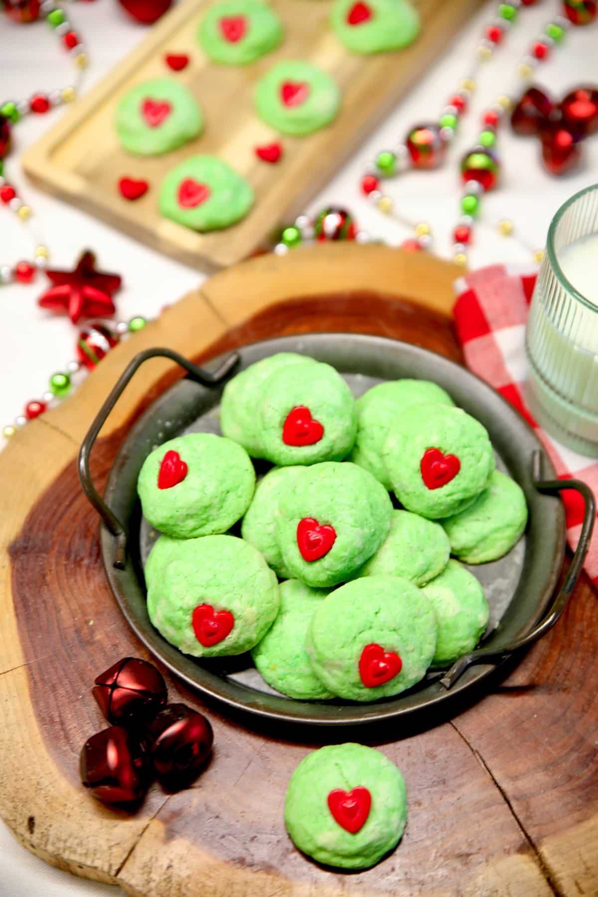 Platter of green Grinch cookies with red candy hearts.