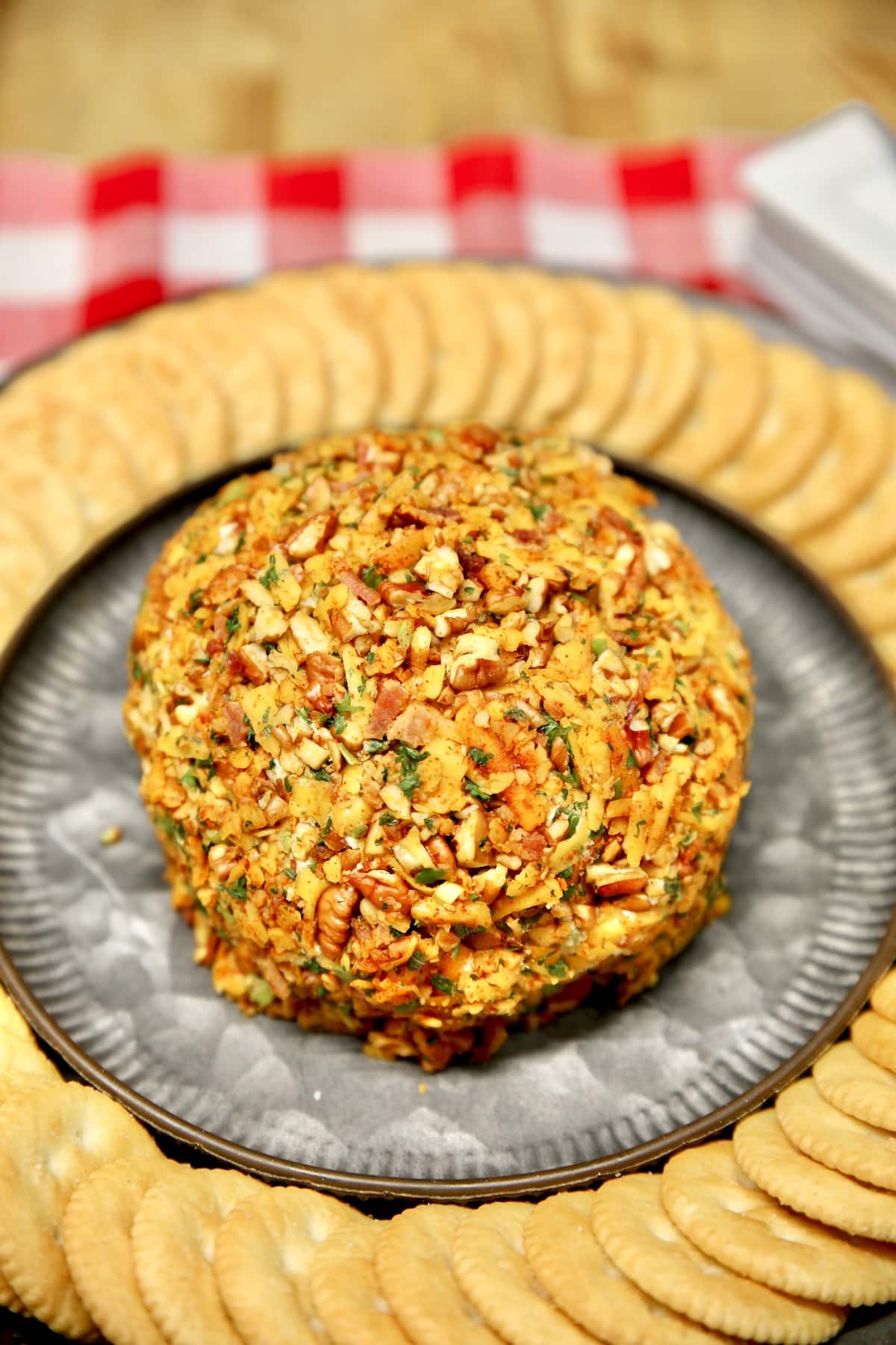 Cheese ball on a platter with Ritz crackers.