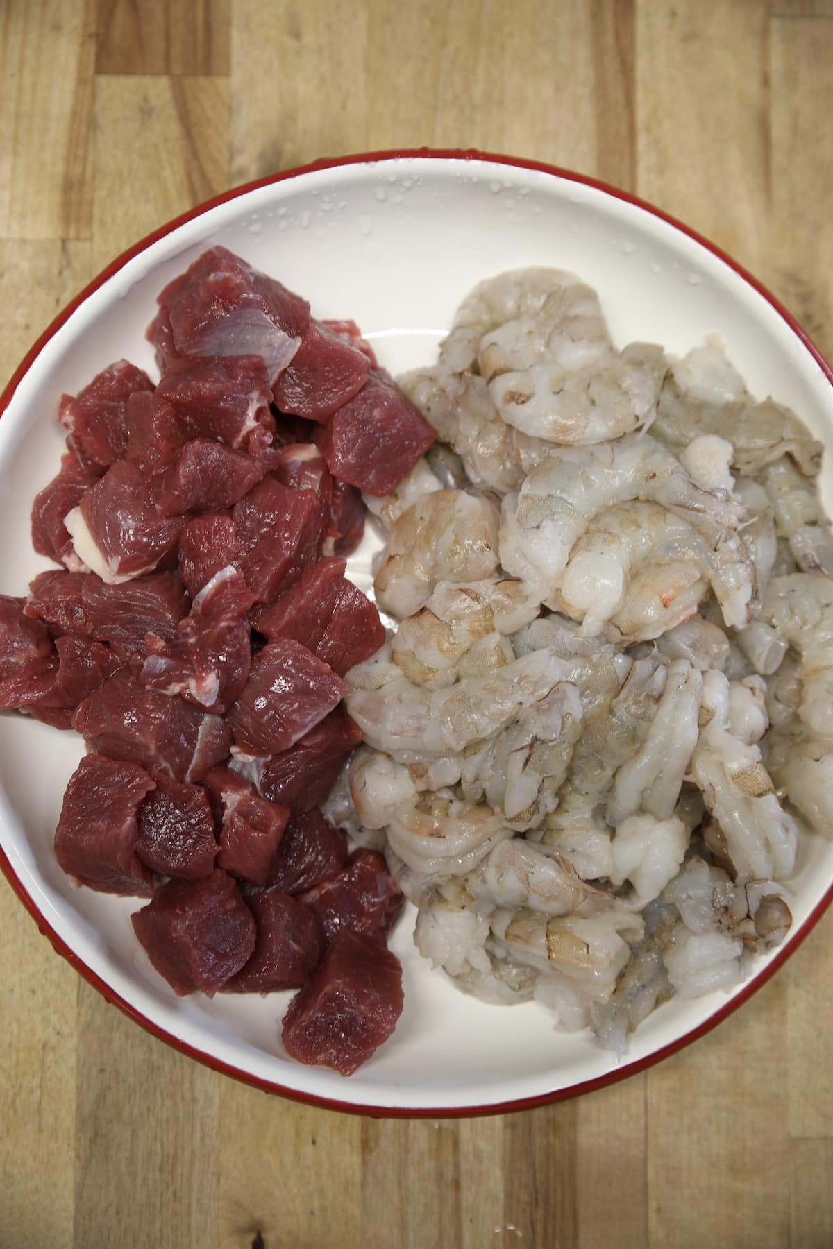 Plate of raw steak cubes and shrimp.