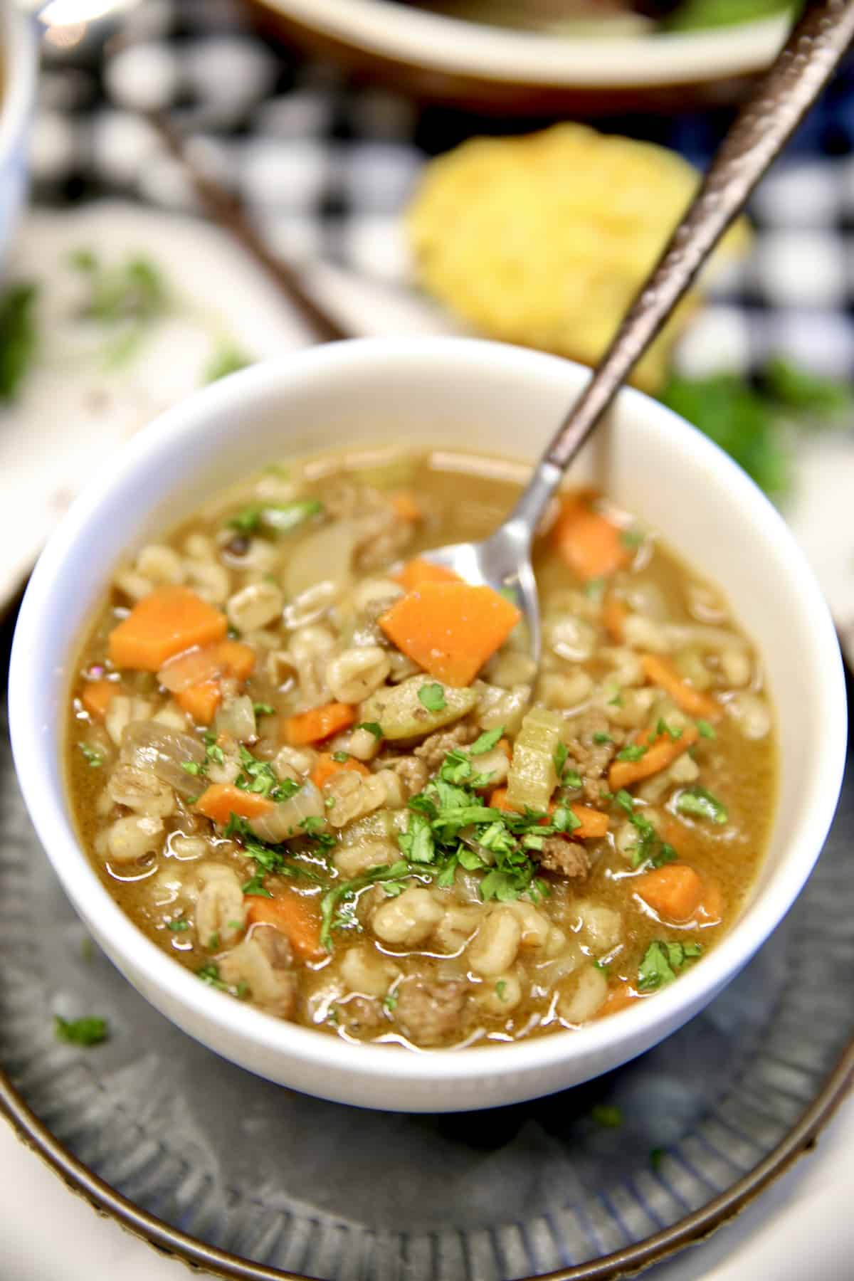 Closeup of a bowl of beef barley soup with a spoon.