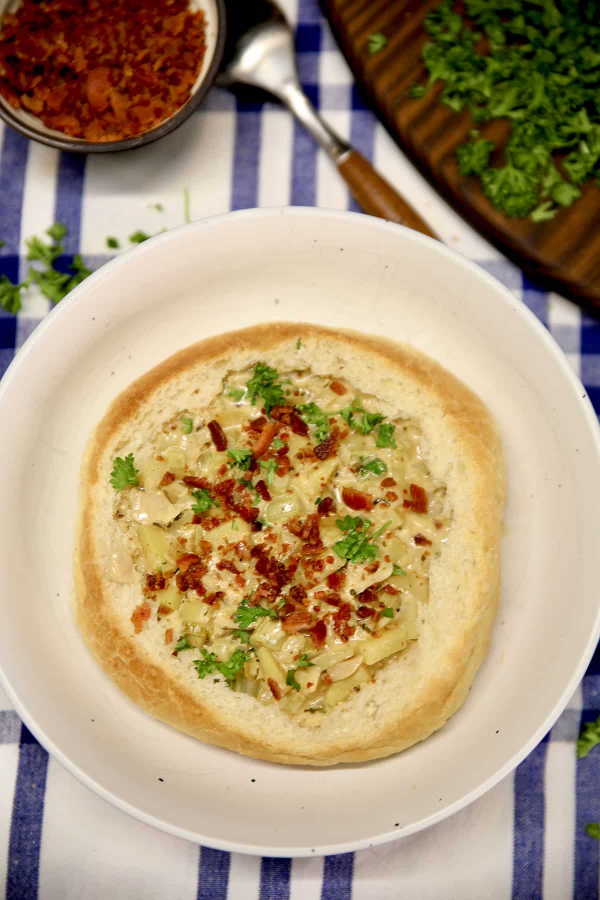 Bread Bowl of Clam chowder garnished with bacon and parsley.