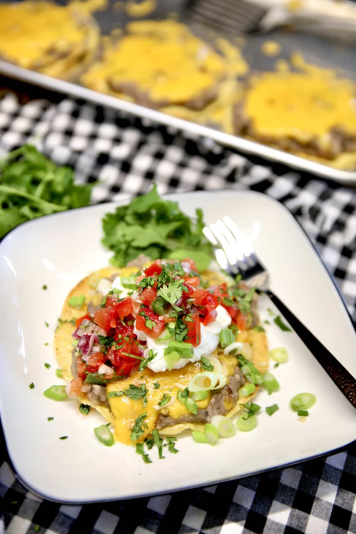 Plate with bean tostada topped with cheese, sour cream, salsa.
