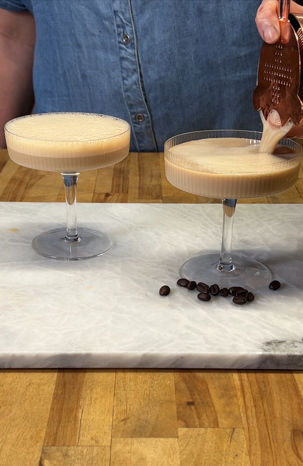 Straining espresso martini into cocktail glasses.