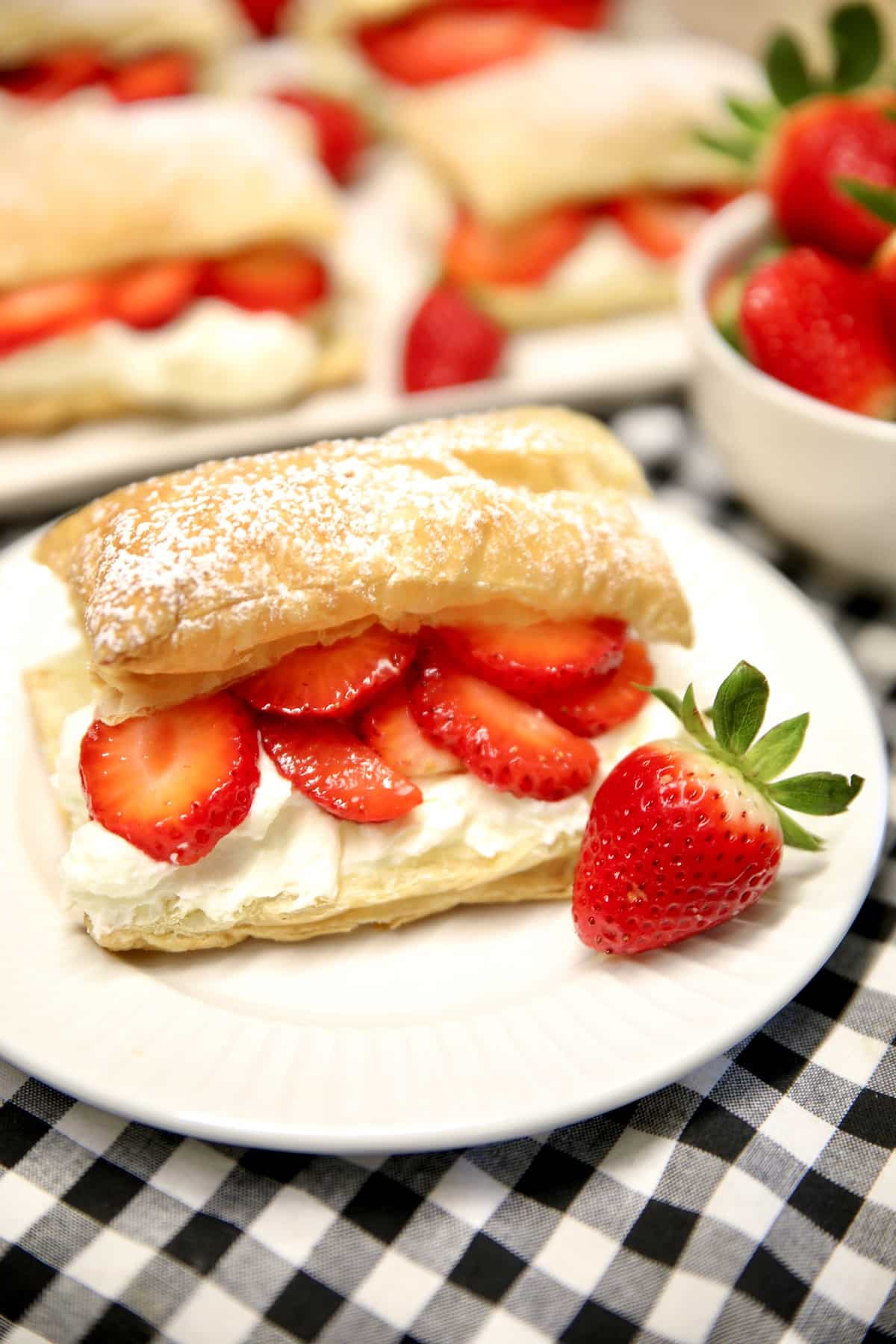 Strawberry Napoleons on a plate with whole strawberry.