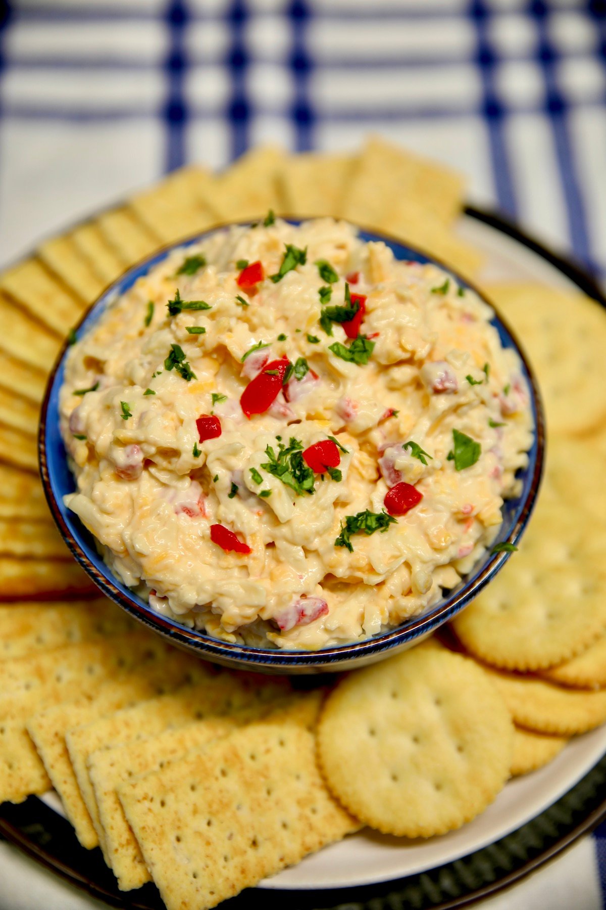 Bowl of pimento cheese on a plate of crackers.