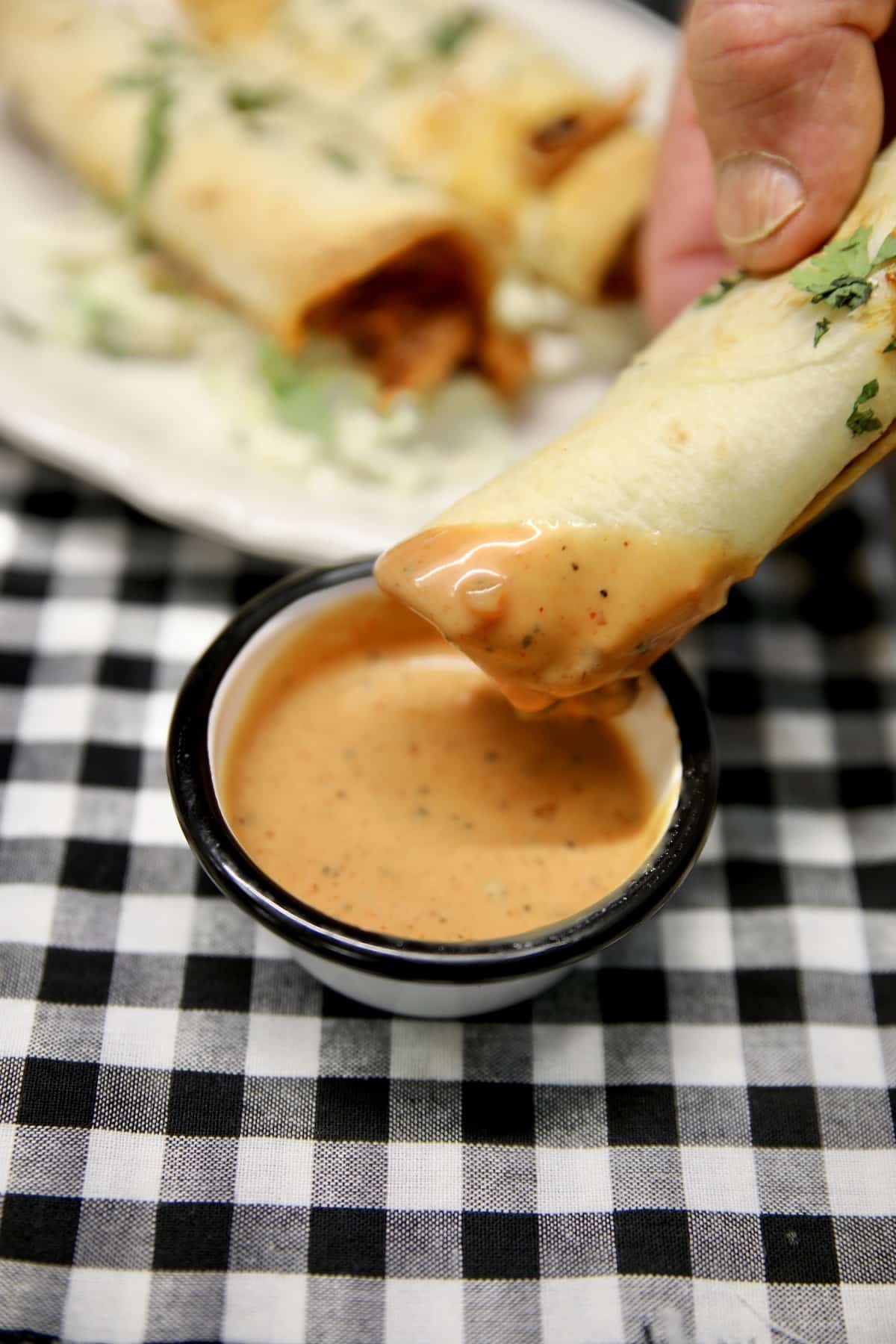 BBQ Chicken taquito dipping in sauce.