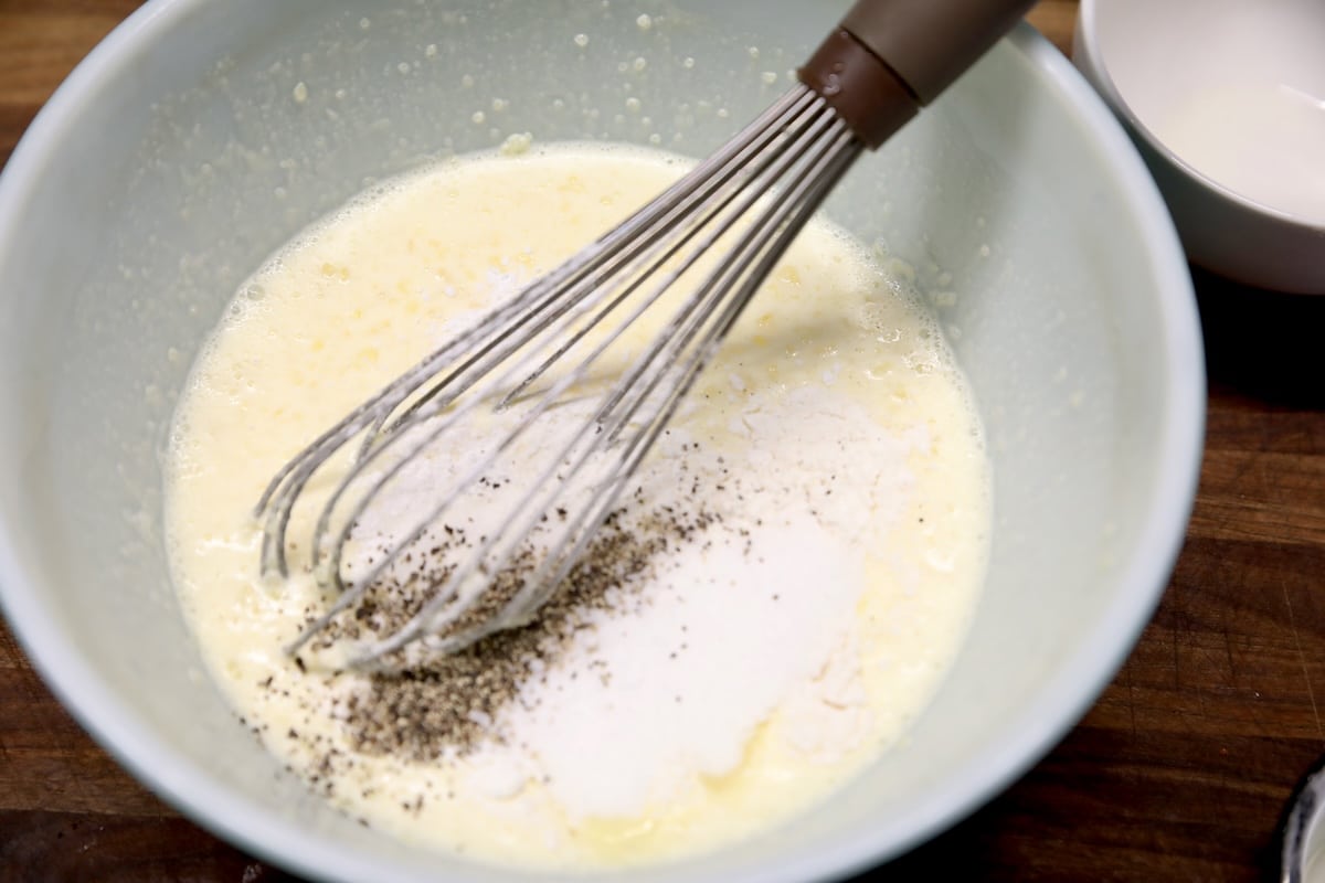 Adding flour, sugar, salt and pepper to egg mixture in a bowl.