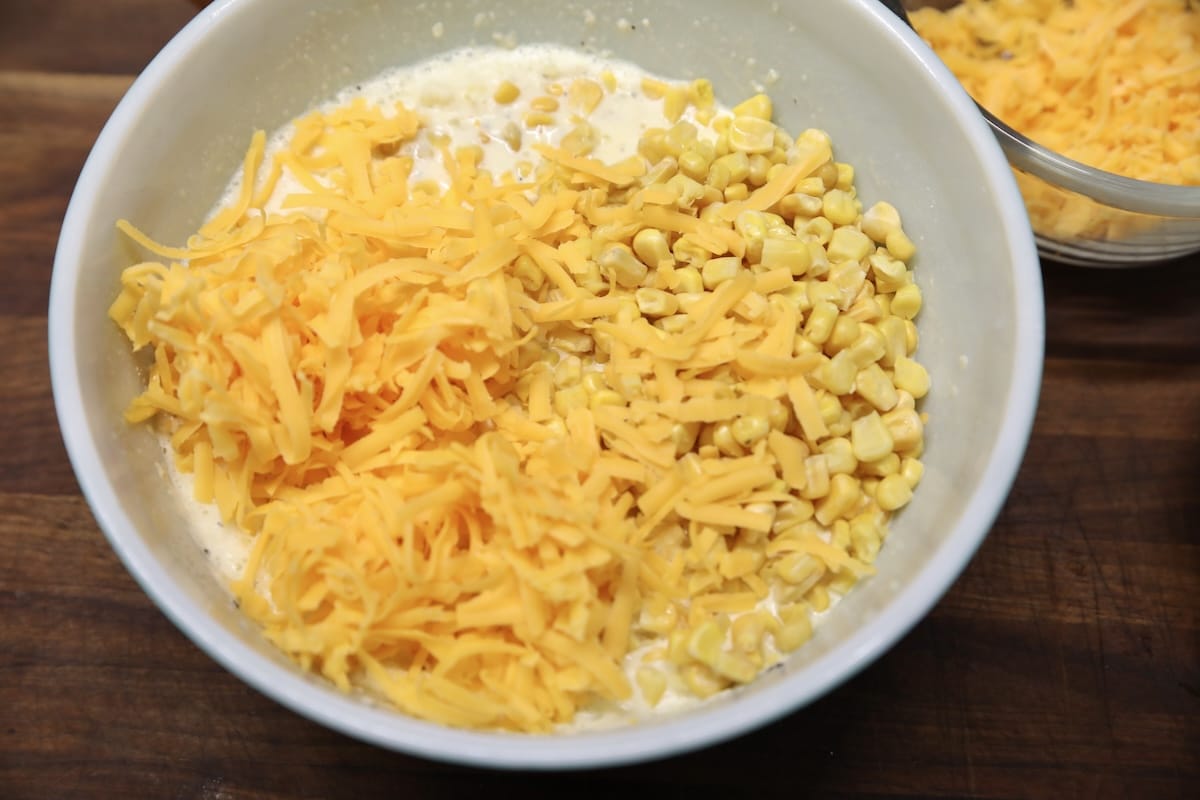 Cheddar cheese and corn in a bowl with egg mixture.
