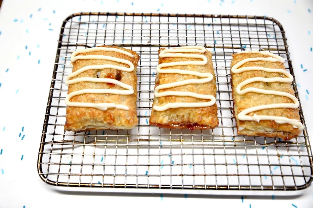 Toaster strudel with cream cheese icing on a wire rack.