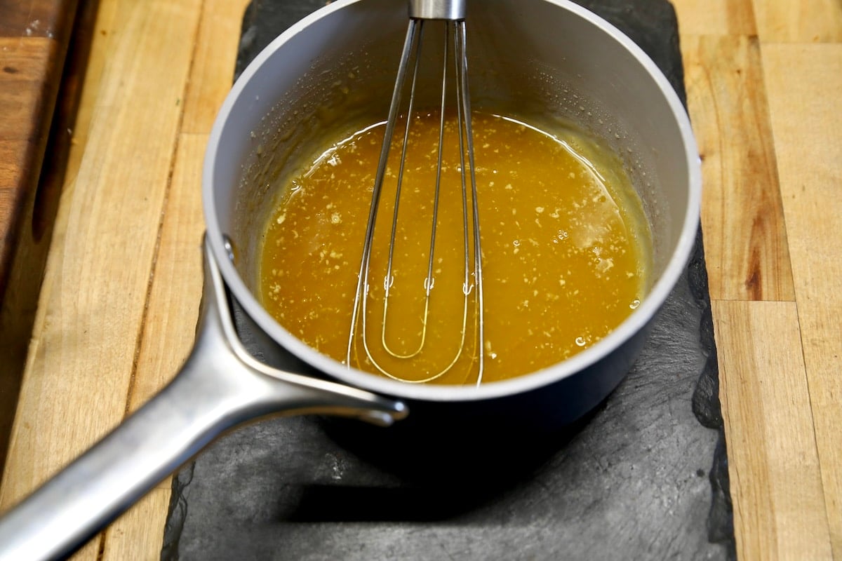 Orange glaze in a pan with whisk.