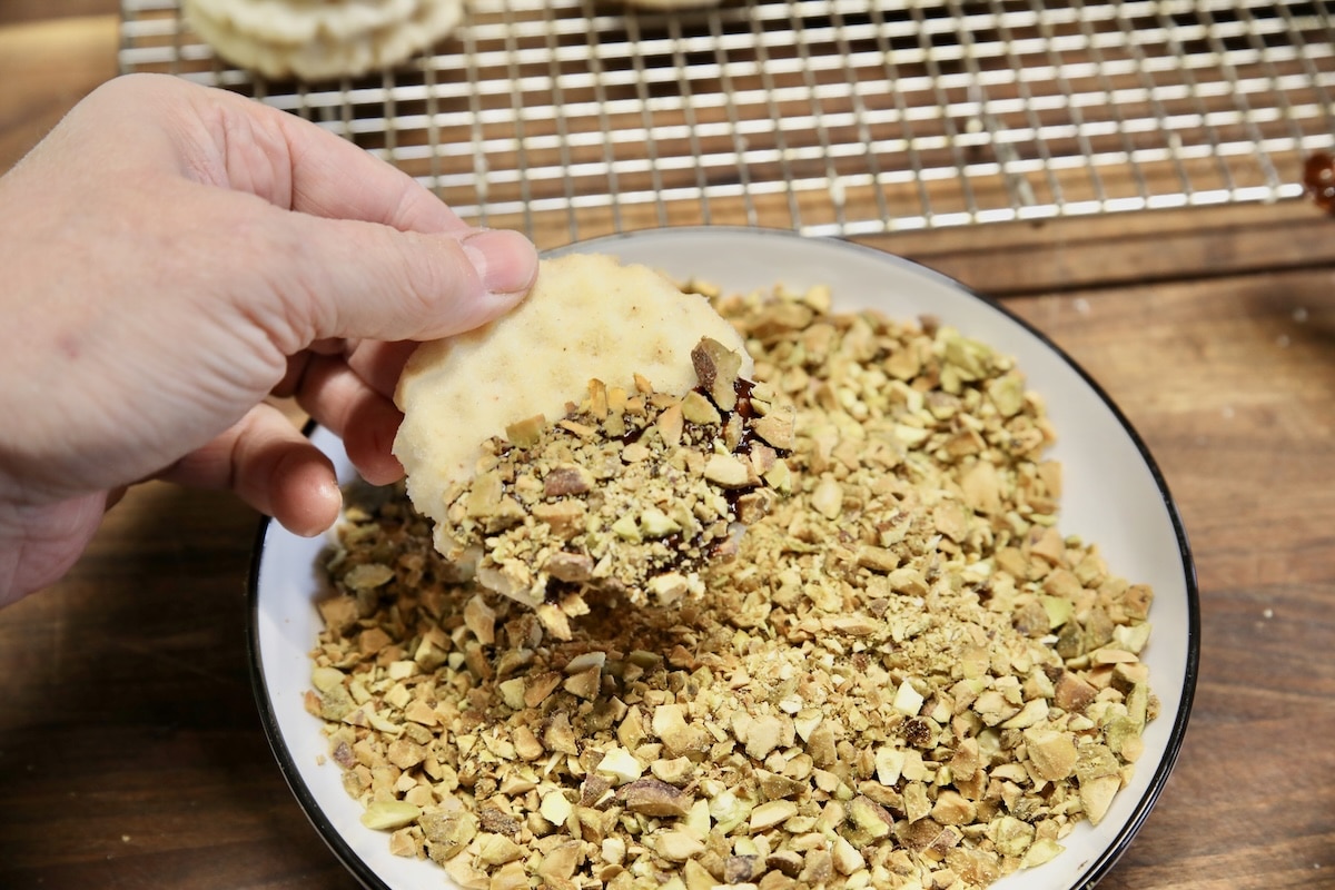 Chopped pistachios sprinkled on chocolate dipped cookie.