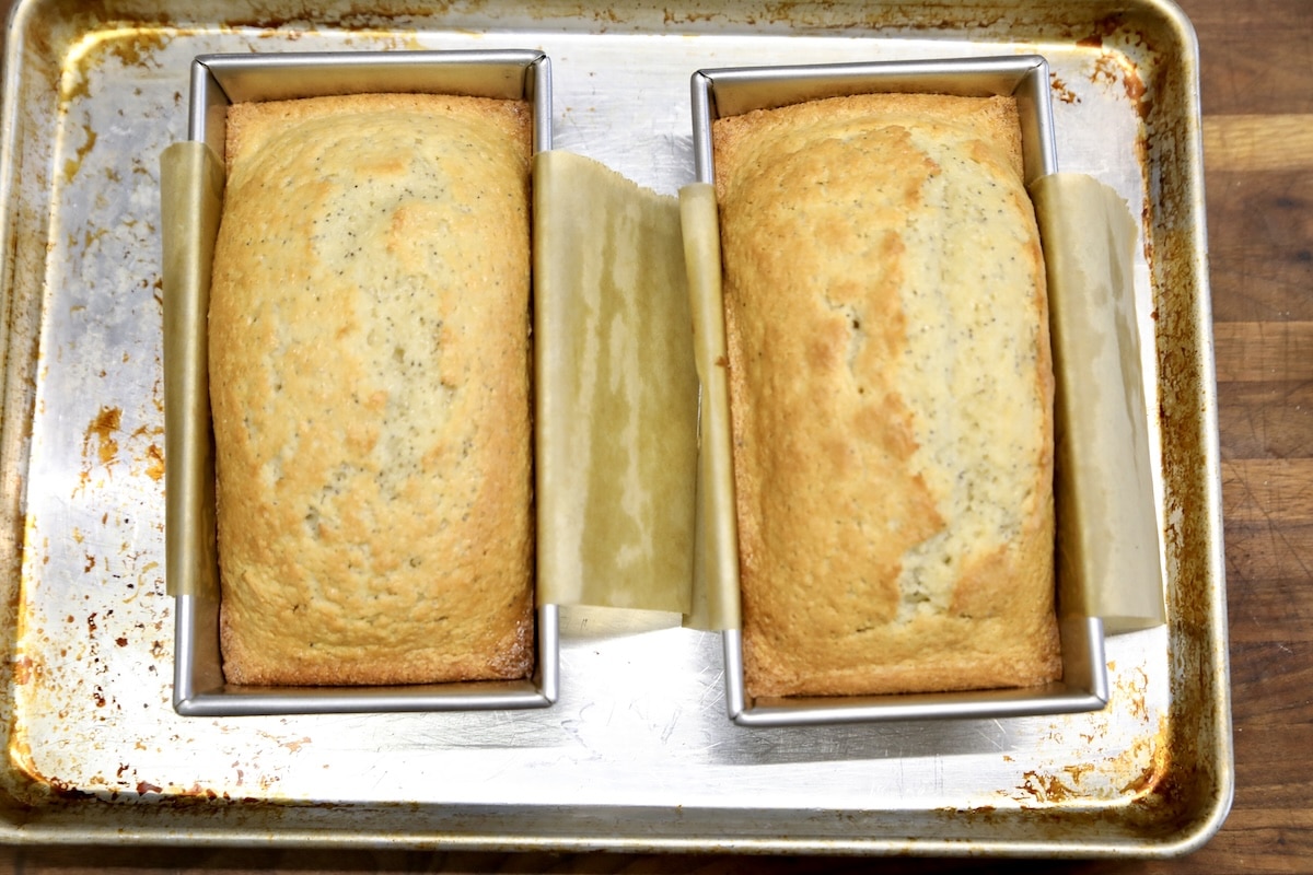 Sheet pan with 2 loaf pans of baked poppy seed bread.