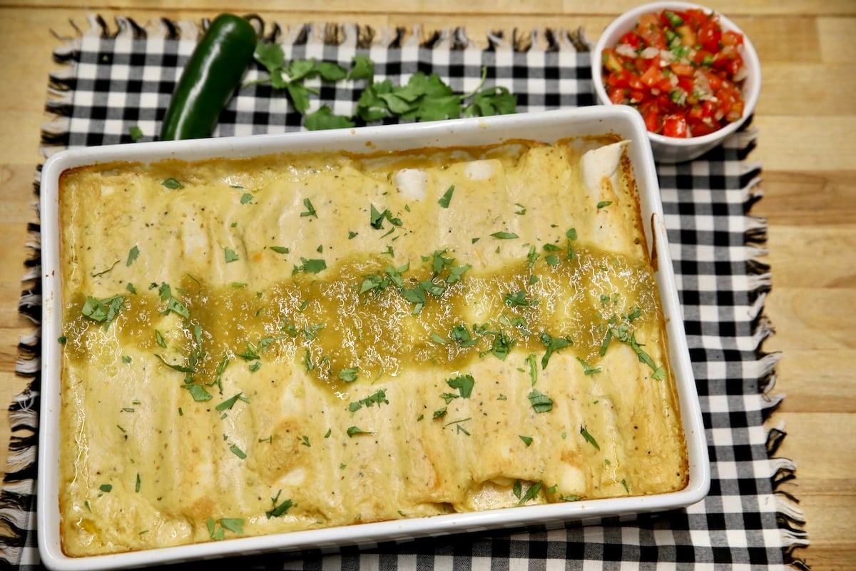 Leftover turkey enchiladas. Pan of baked enchiladas with salsa verde and cilantro garnish.