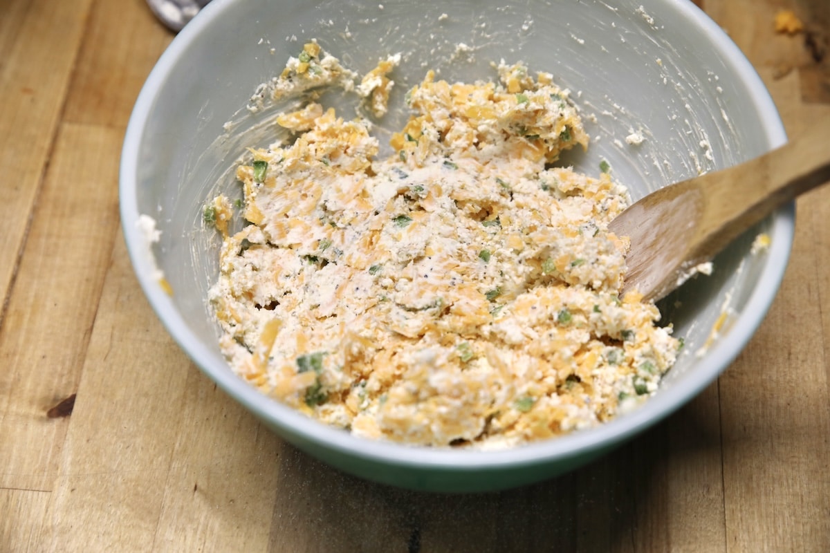 Mixing creamy filling for enchiladas in a bowl.