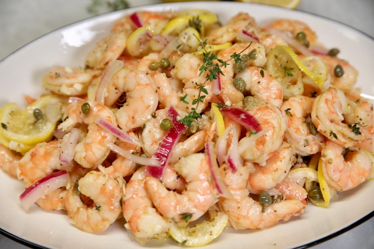 Platter of pickled shrimp with red onion and lemons.