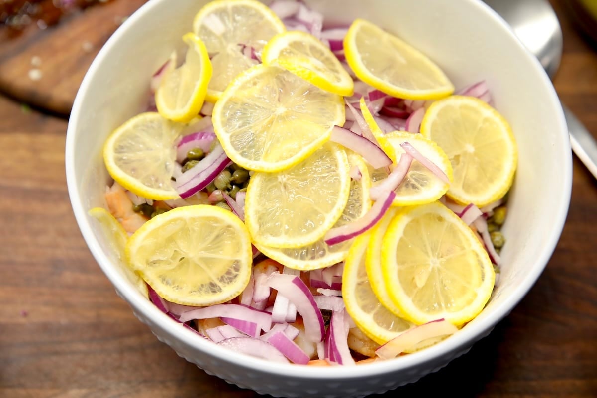 Bowl of shrimp, red onion, lemon slices.