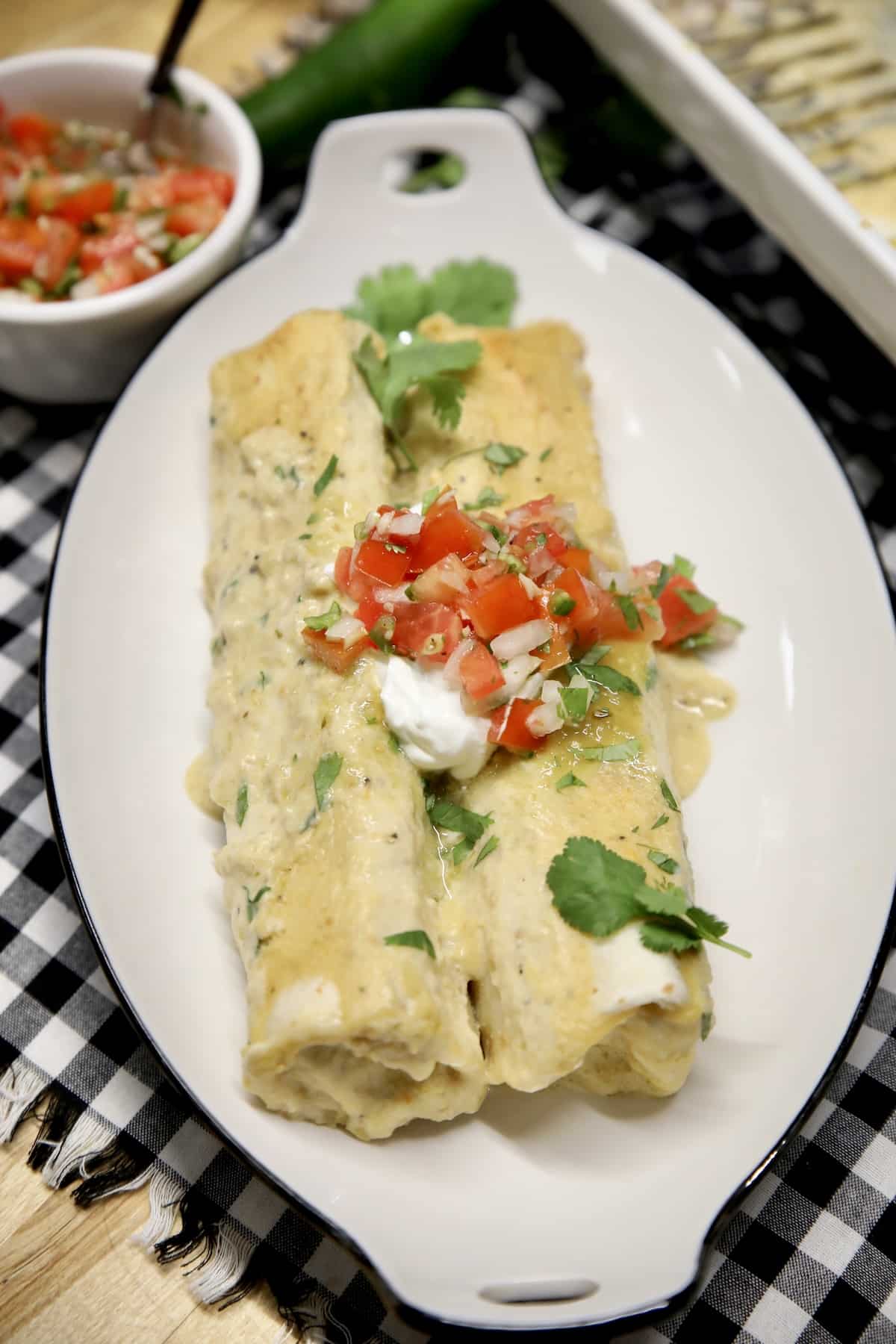 Platter of turkey enchiladas with salsa verde sauce, pico de gallo.