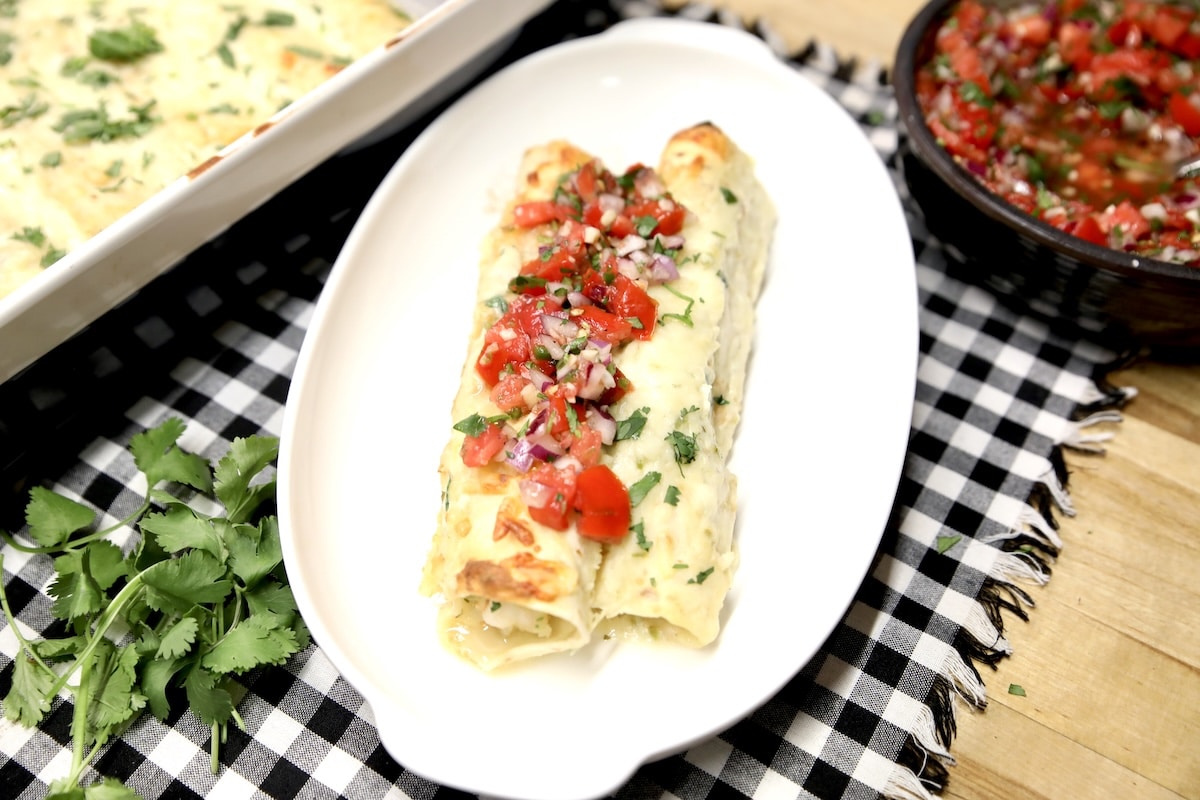 2 seafood enchiladas on a plate with pico de gallo.