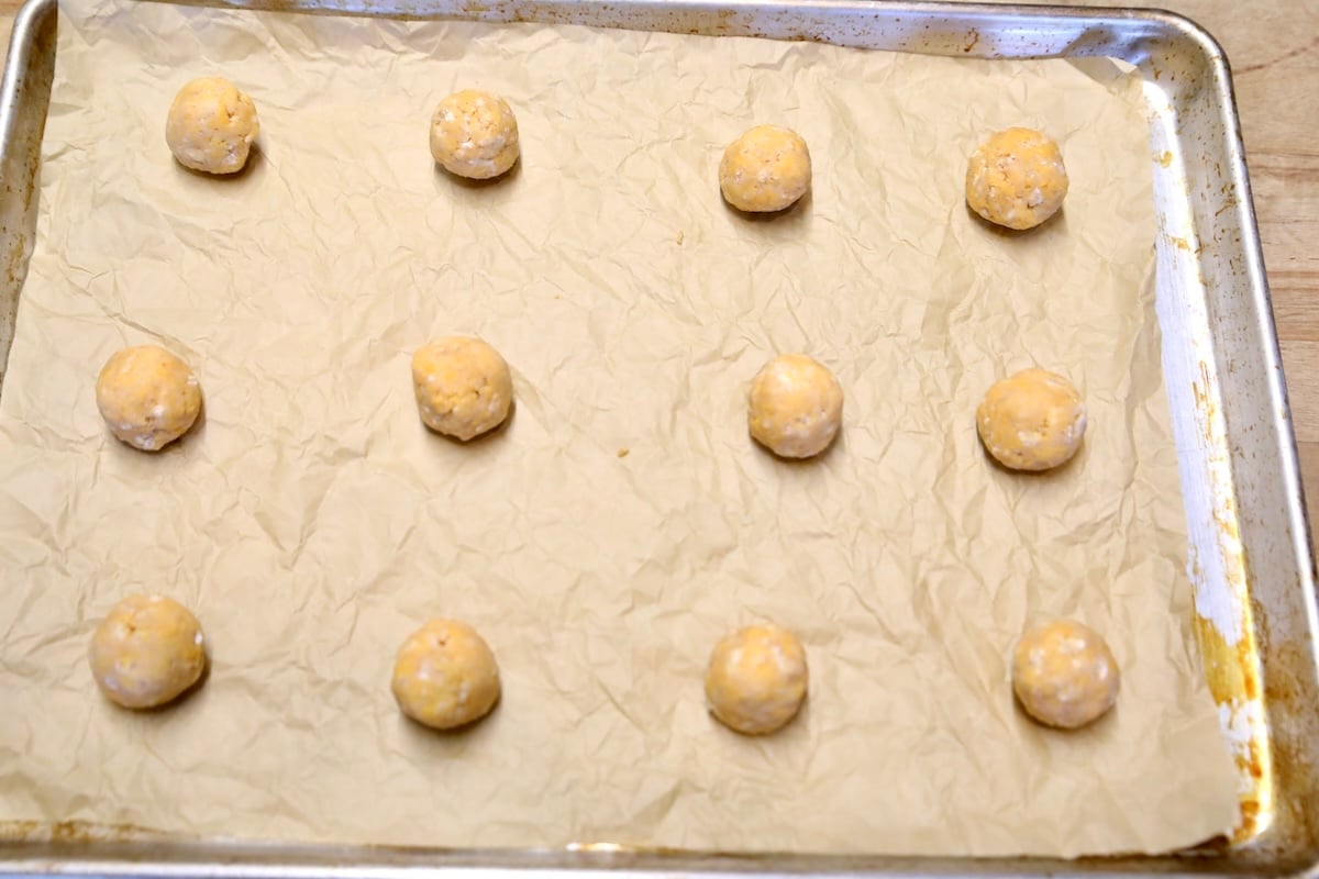 Cheese wafer dough balls on a cookie sheet.