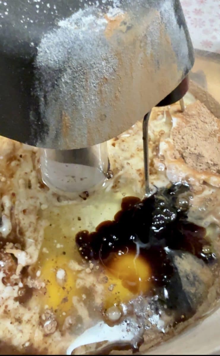Adding wet ingredients to mixer bowl for chocolate cake.