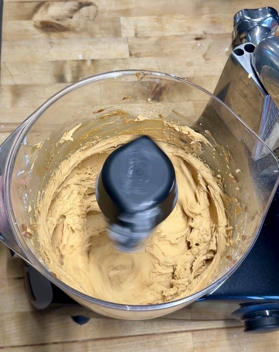 Butter and caramel mixed for frosting in a mixer bowl.