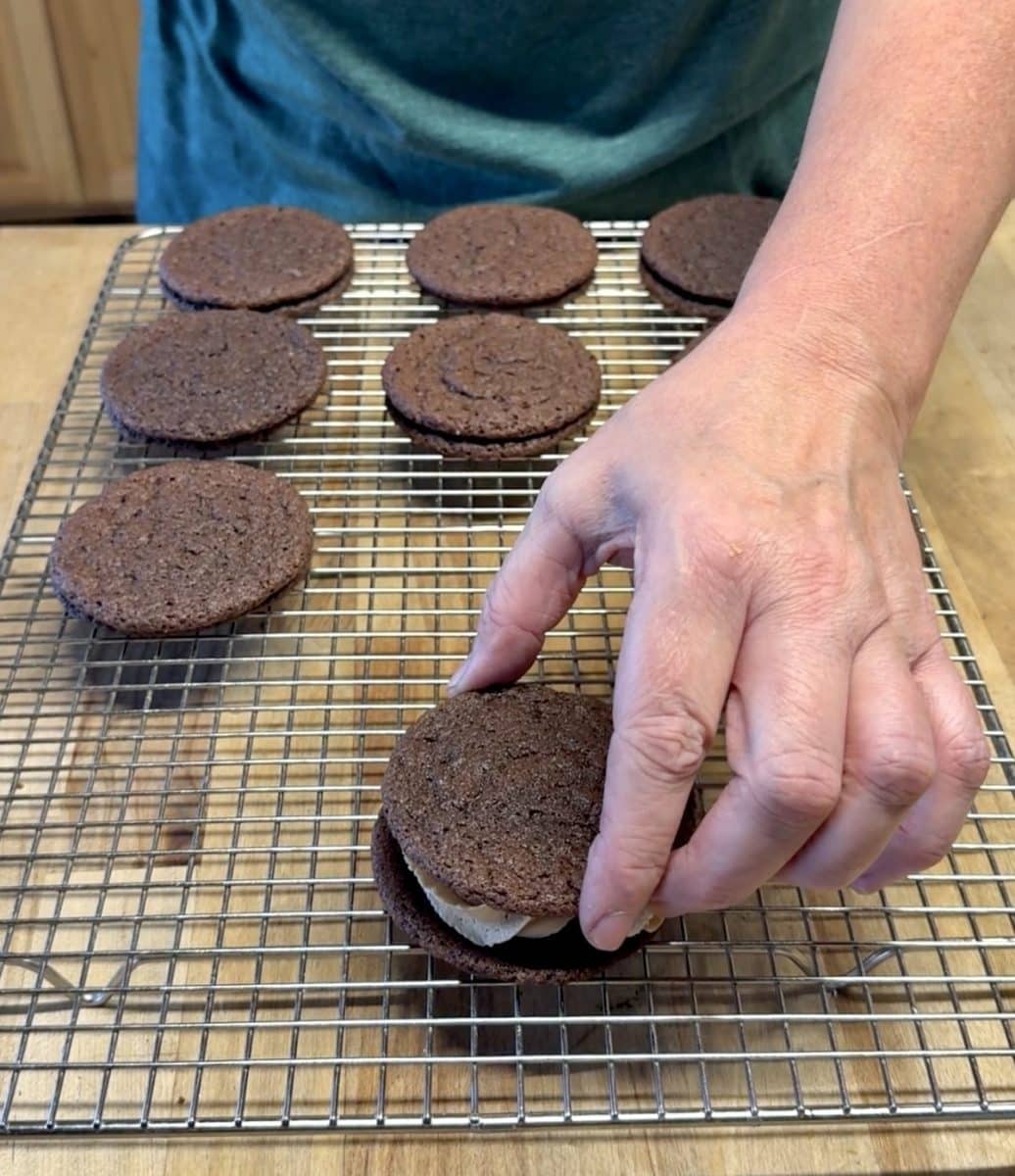 Making chocolate cookies filled with caramel frosting.
