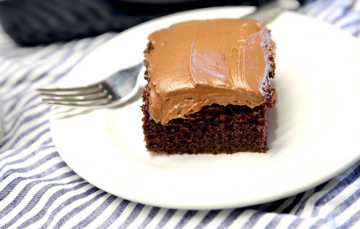 Slice of chocolate cake with frosting on a plate.
