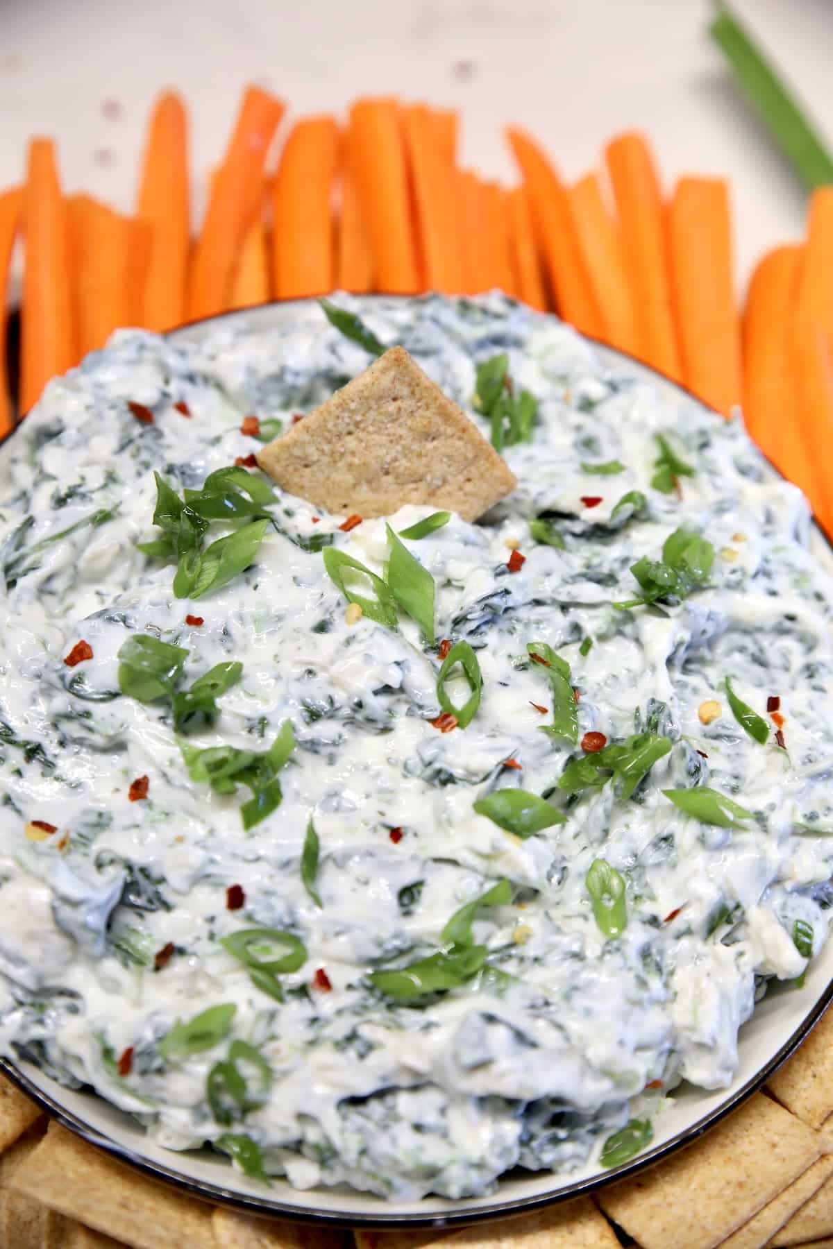 Ranch Spinach dip in a bowl with carrots and crackers.