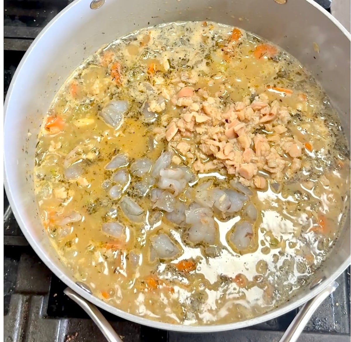 Adding clams and shrimp to pan for soup.