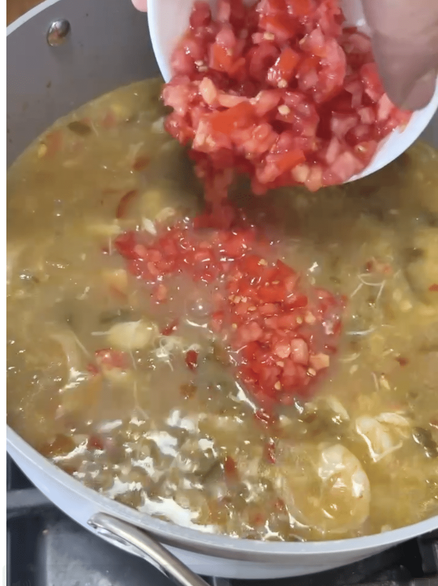 Adding tomatoes to soup.