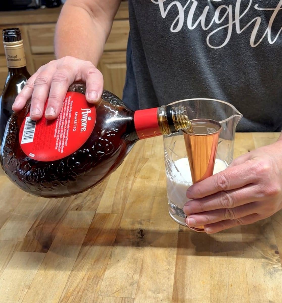 Measuring amaretto with cocktail jigger.