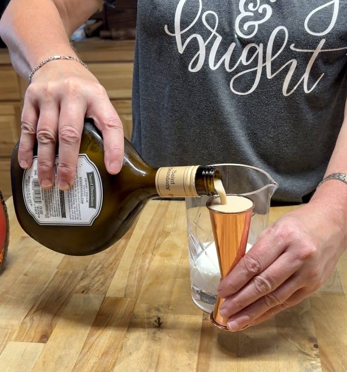 Pouring Irish cream into a cocktail jigger.