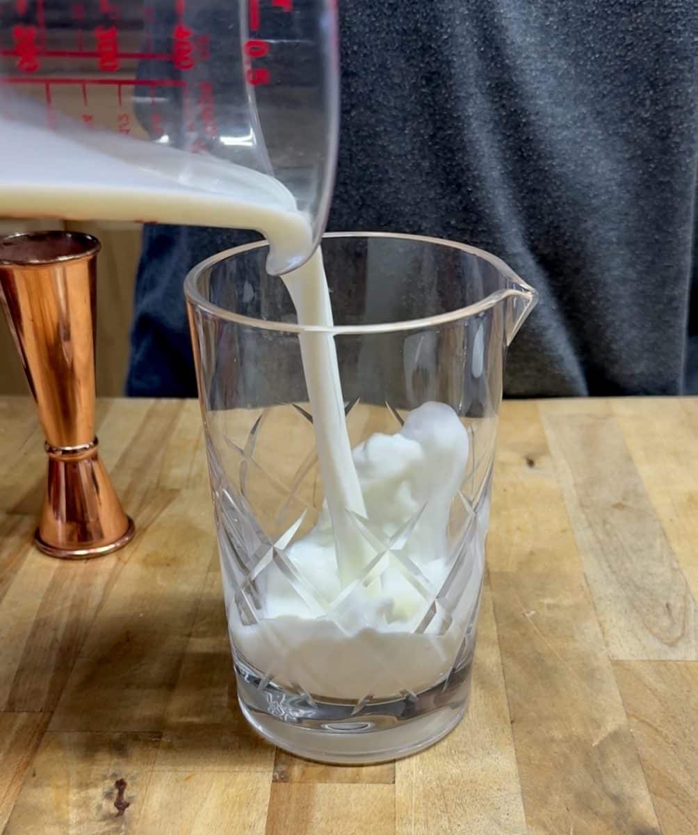 Pouring milk into a mixer glass for cocktail.