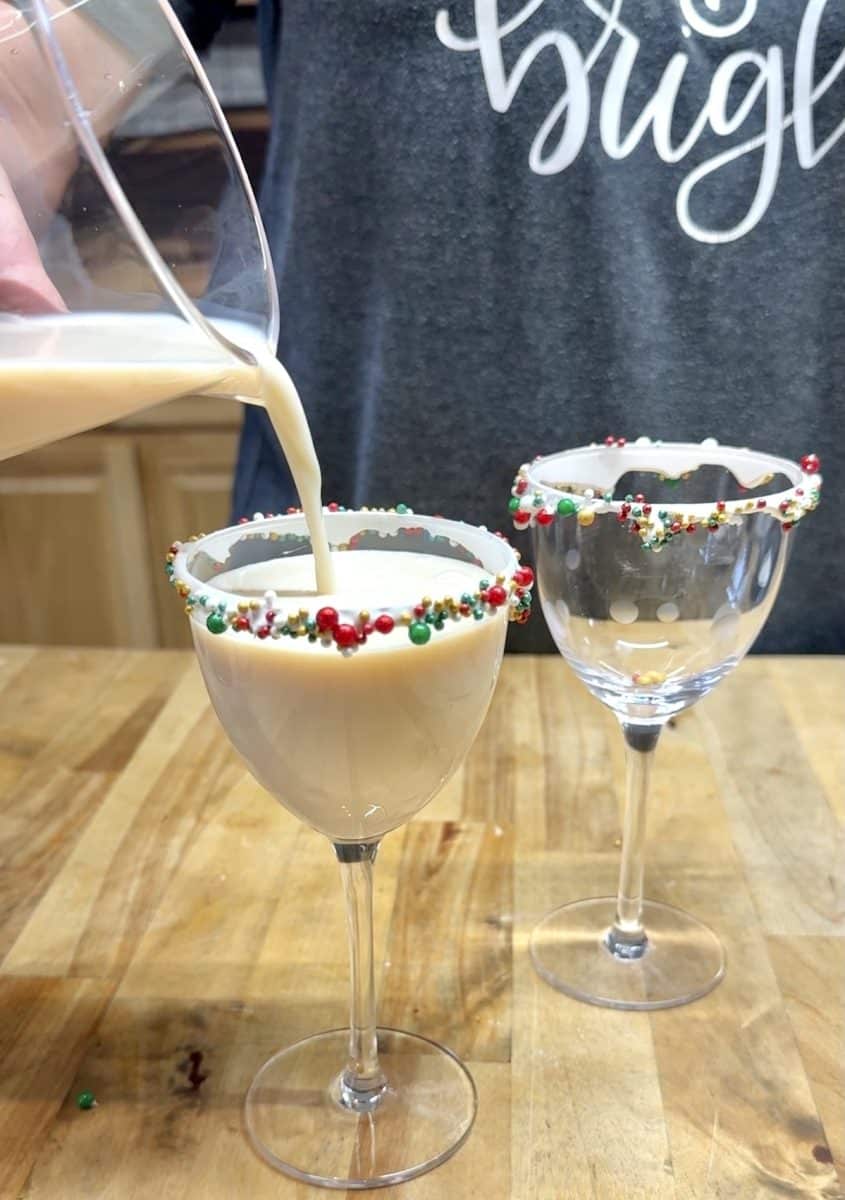 Pouring creamy cocktail into small cocktail glasses.
