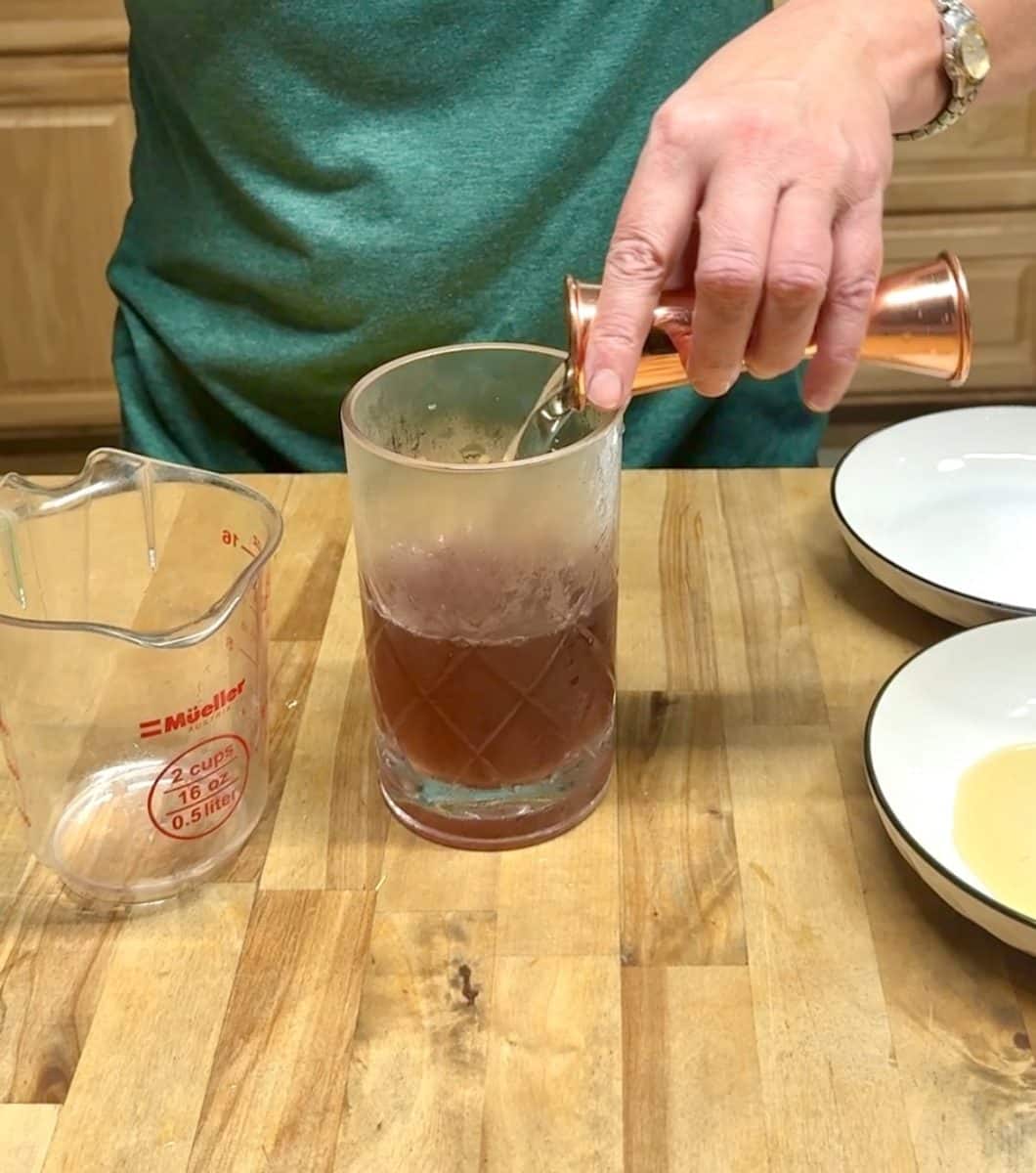 Adding simple syrup to a mixer glass.