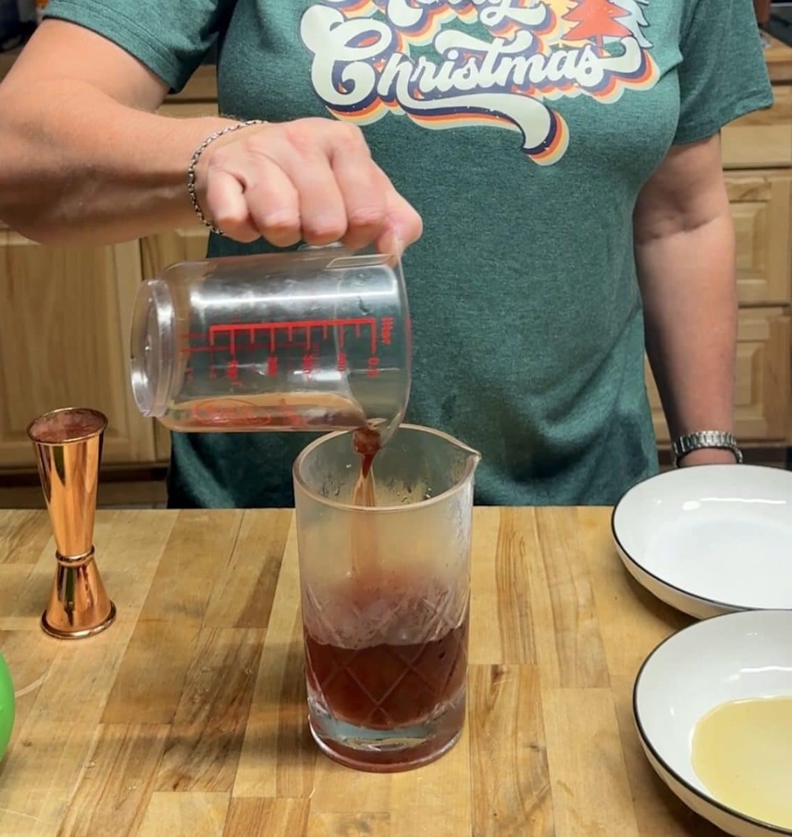 Pouring cranberry juice into a mixing glass.