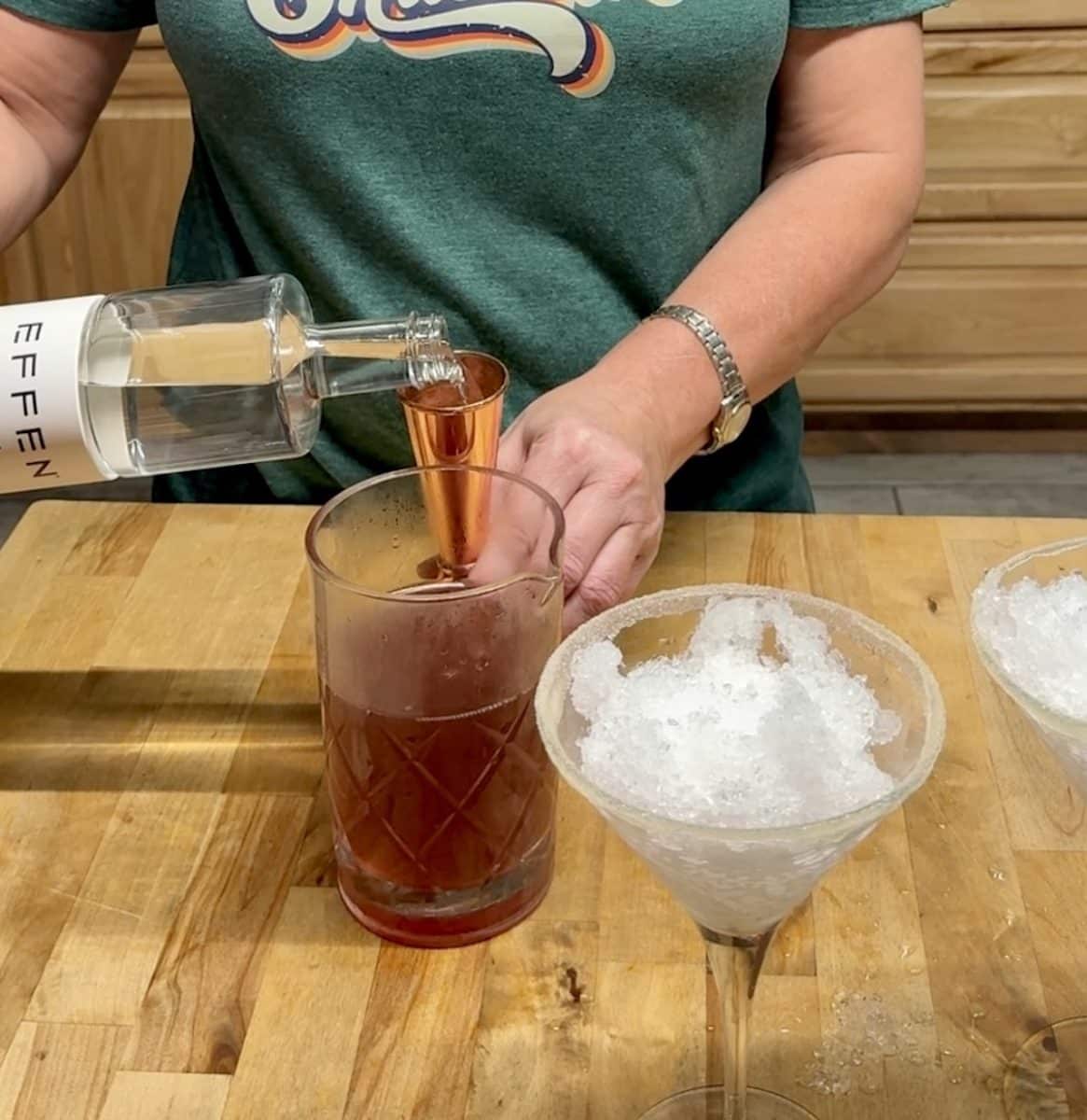 Measuring vodka for cranberry cocktail.